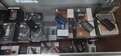 A display case filled with various vape products, including mods, tanks, and e-liquids, in a store setting.