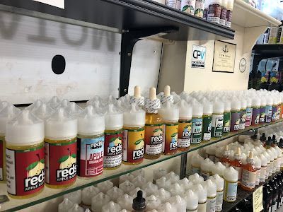 Shelves of vape juice bottles, various flavors and colors, inside a store.