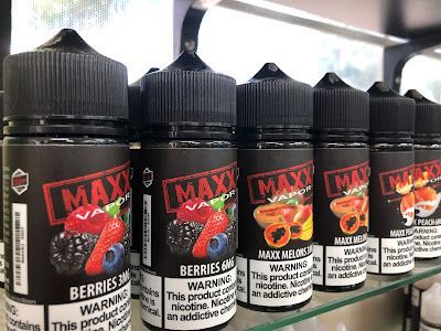 Row of MAX Vapor e-liquid bottles. Flavors include berries, papaya. Black bottles, red and white labels.
