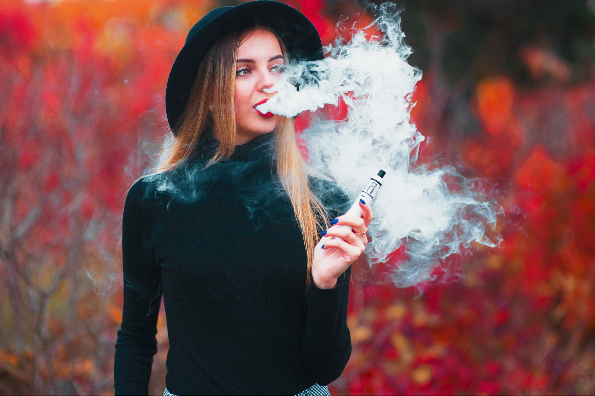 Woman vaping with autumn foliage background