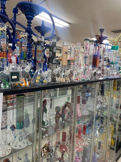 Glass pipes and bongs on display inside a retail store. Rows of colorful glass pieces behind glass display cases.