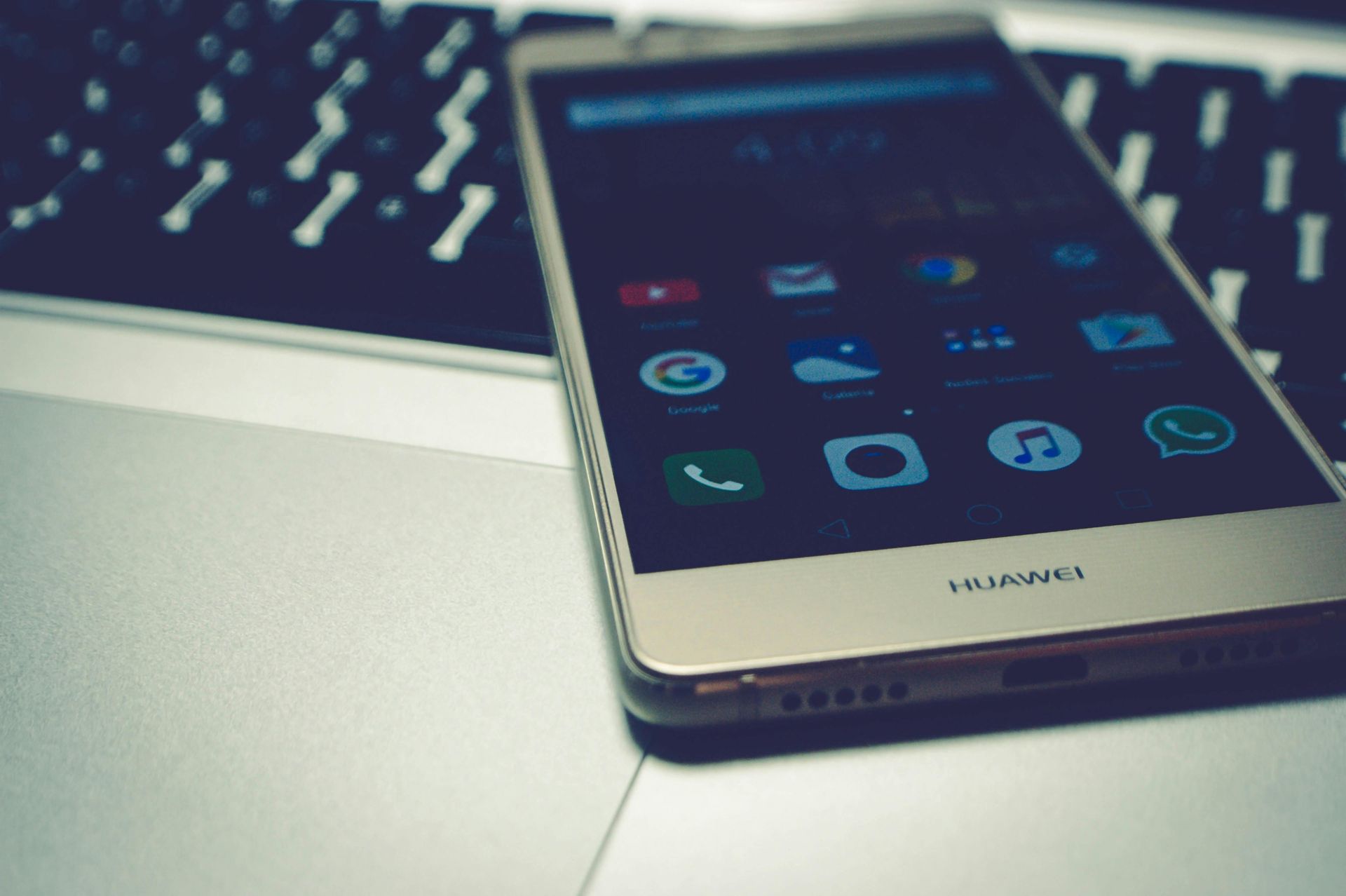 Goldenes Huawei-Smartphone auf einer Laptop-Tastatur. Auf dem Bildschirm des Telefons sind App-Symbole zu sehen.
