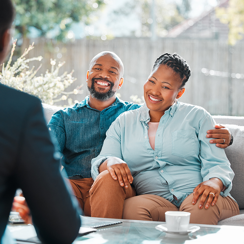 Couple smiling while meeting with a financial advisor outdoors.
