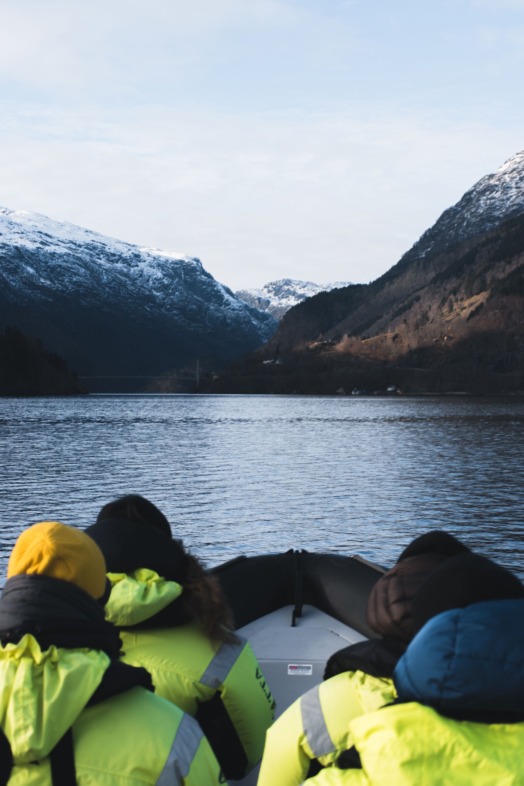 People in a boat on a lake with snow-covered mountains in the background.