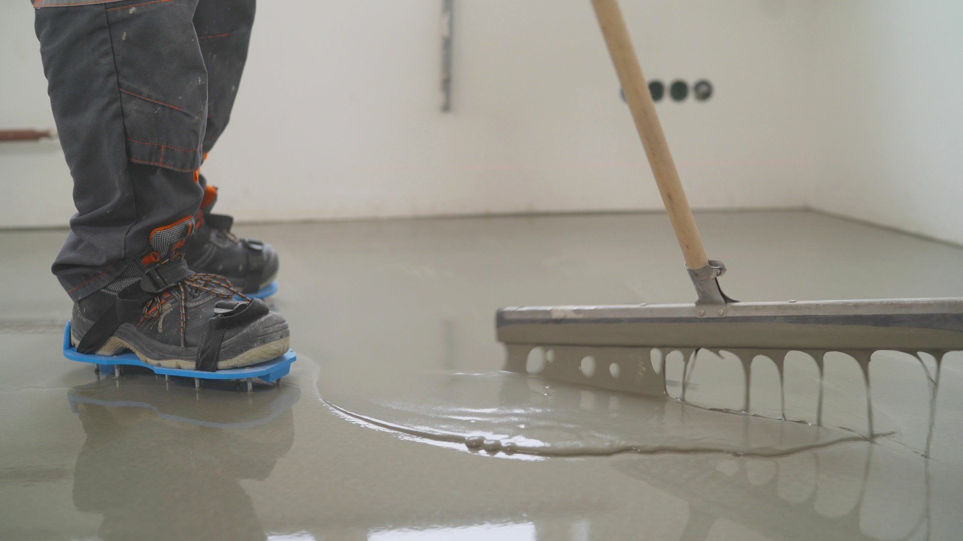 Man using a roller to apply self-leveling cement mortar as floor covering.