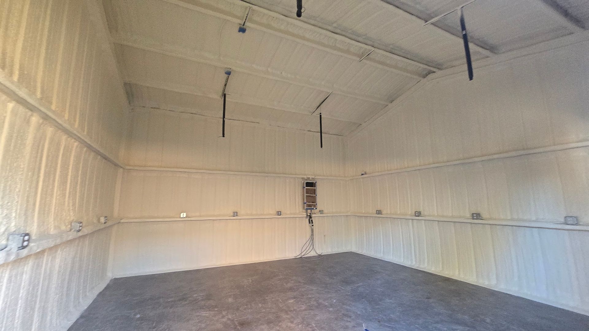 Empty white metal warehouse interior with concrete floor and overhead lights