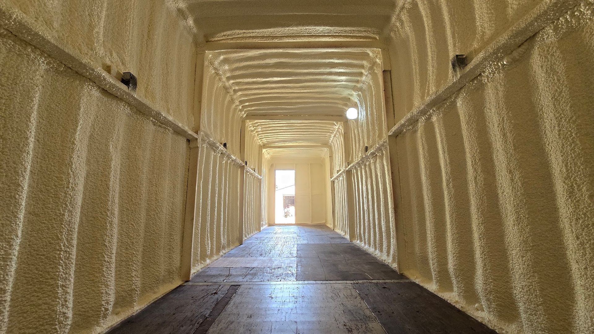 Empty beige corridor with a bright doorway at the far end