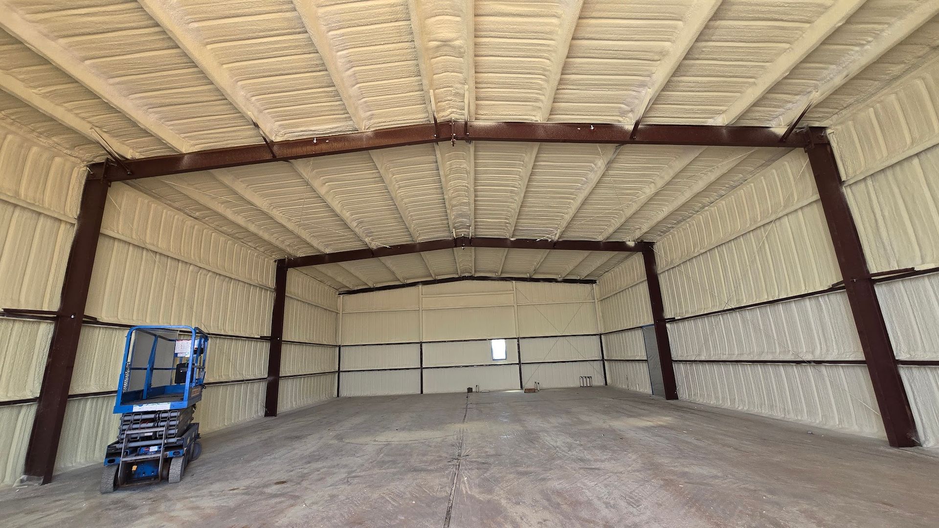 Empty warehouse interior with a large dirt pile and a blue lift on the left