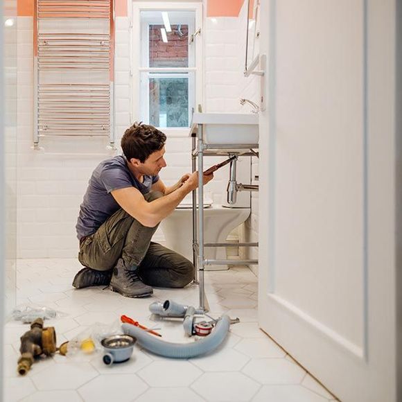 Young Man Fixing a Leak Under the Bathroom Sink — San Jose, CA — Efficient Plumbing & Sewer