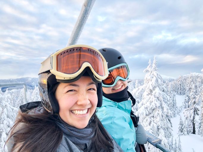 two girls on a ski lift smiling