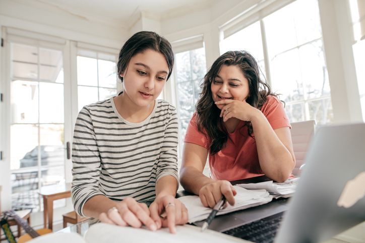 A teen girl and her mom looking at a computer together