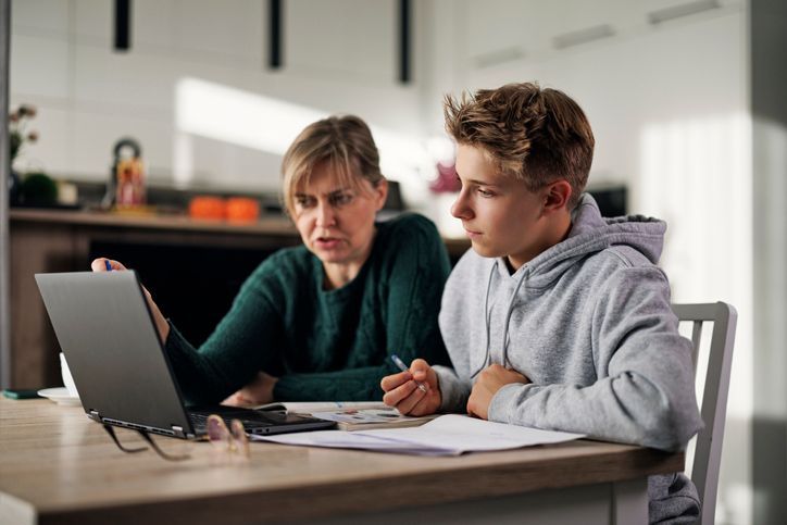 mom and teen son sitting at table looking at a laptop