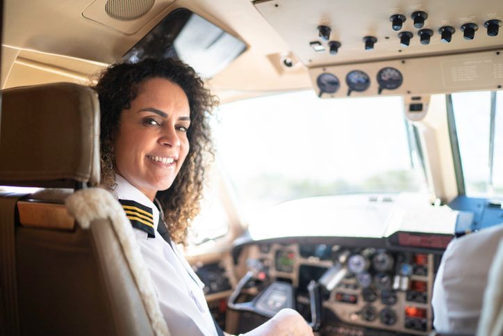 Young female pilot in cockpit of small airplane.