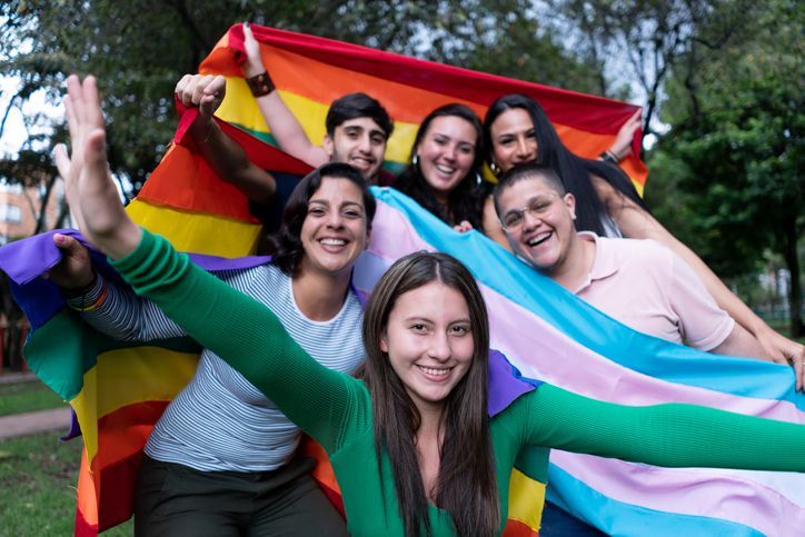 A group of students holding pride and transgender flags and smiling