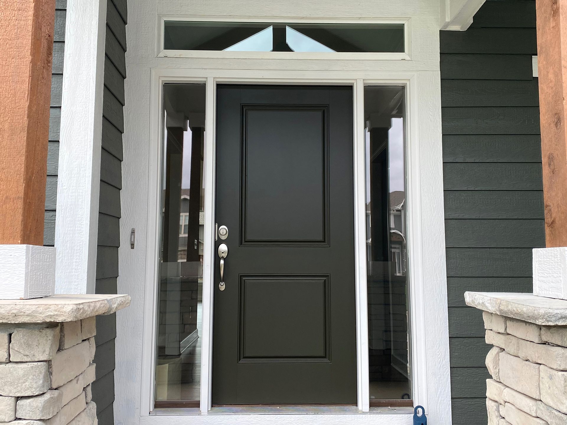 The front door of a house with a black door and a white trim.