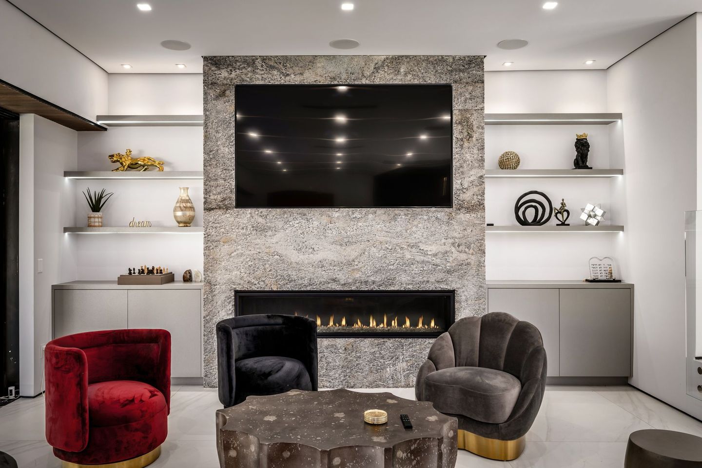 A living room with a fireplace , chairs and a flat screen tv.