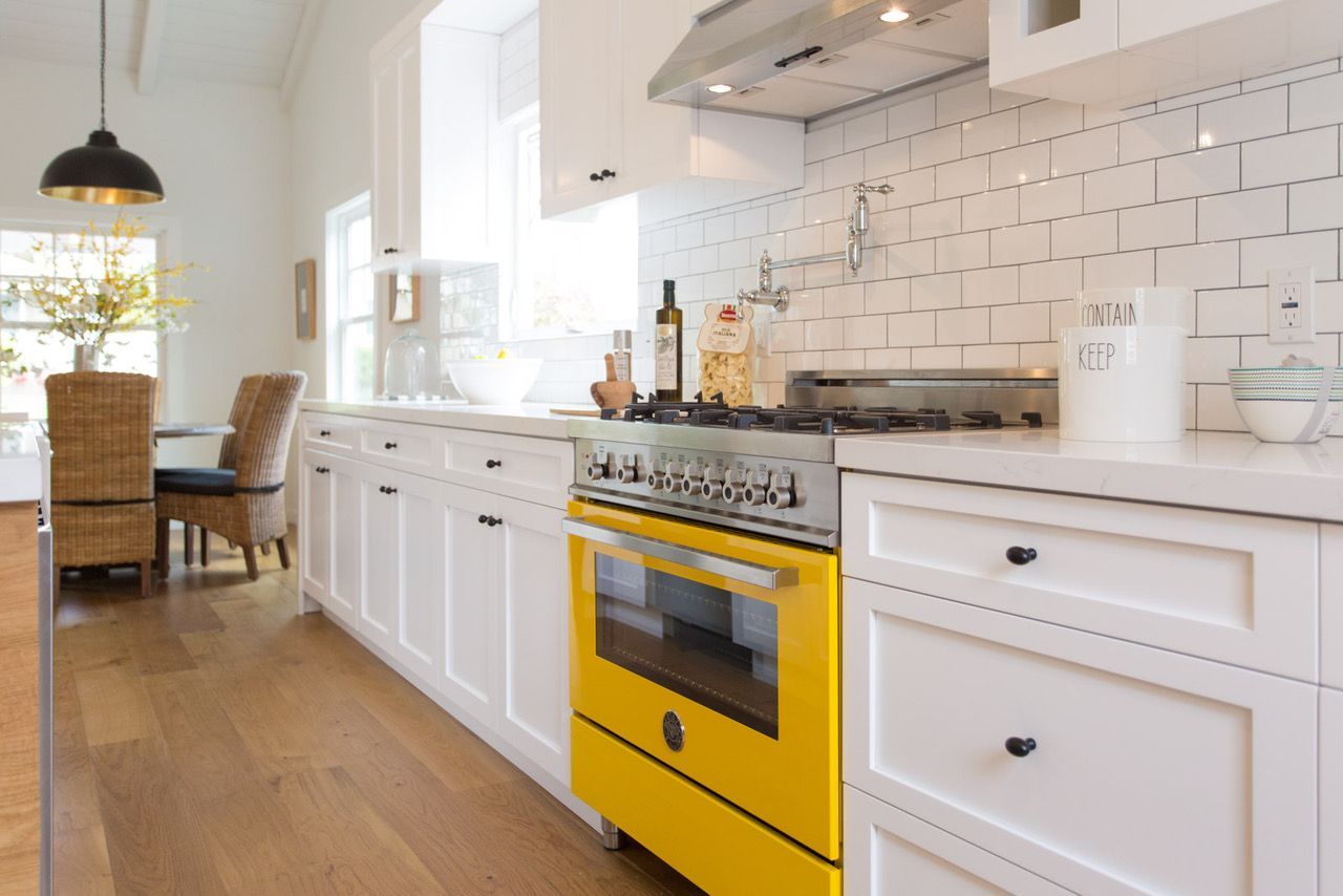 A kitchen with a yellow stove and white cabinets