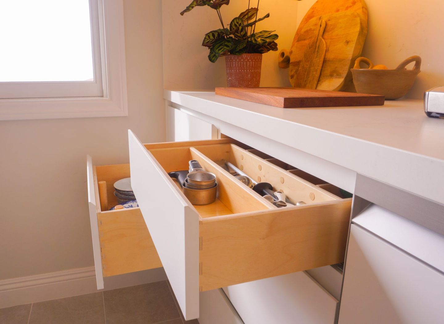 A kitchen with two drawers open and a plant on the counter.