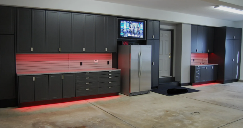 A garage with lots of cabinets and a refrigerator.