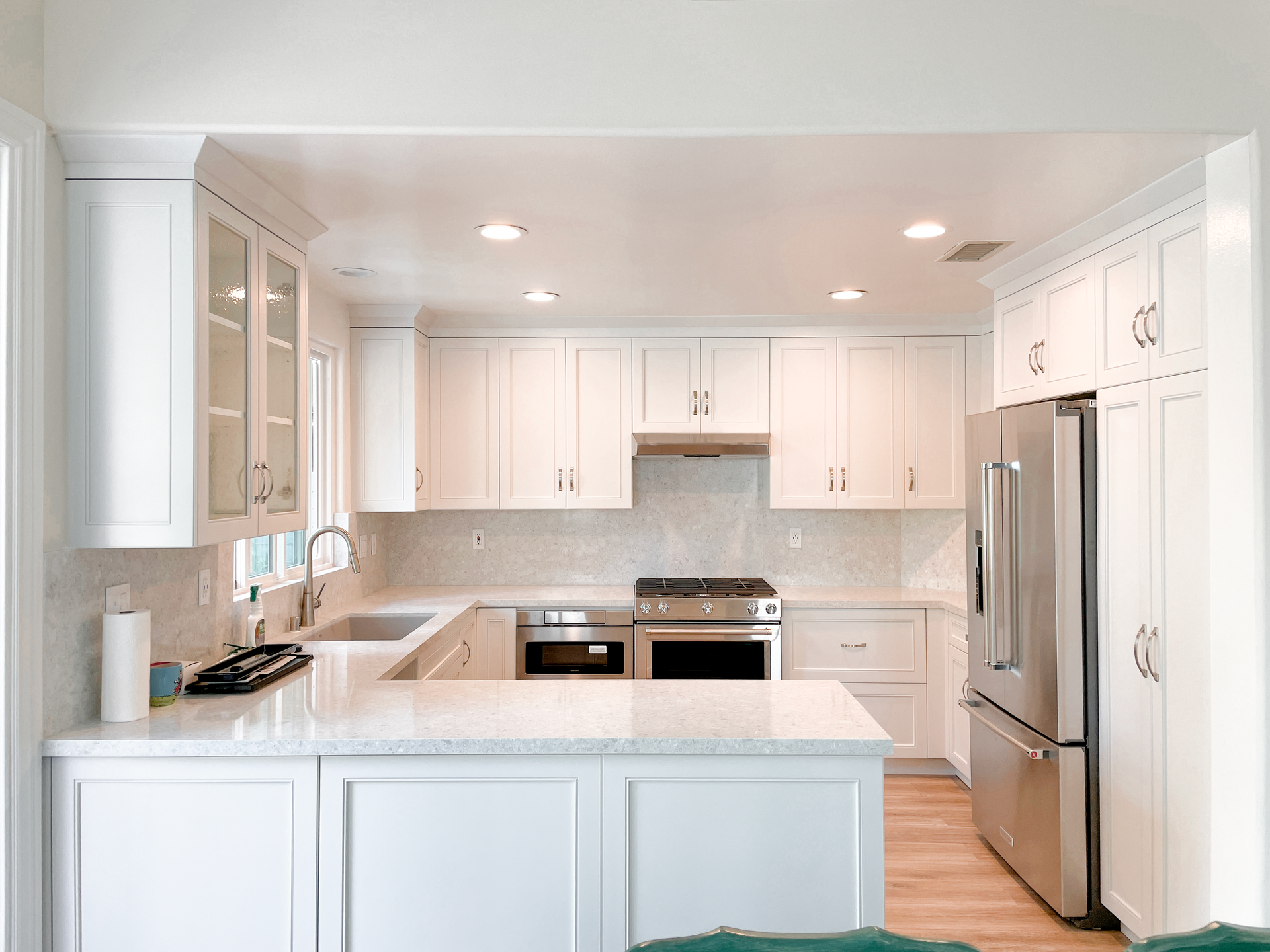 A kitchen with white cabinets , stainless steel appliances , and a large island.