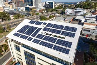 Solar panels on a building roof in a city, generating sustainable energy.