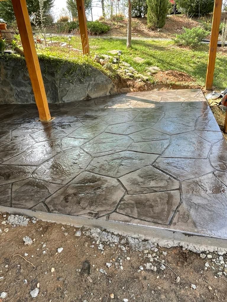 A concrete patio with a wooden structure in the background.