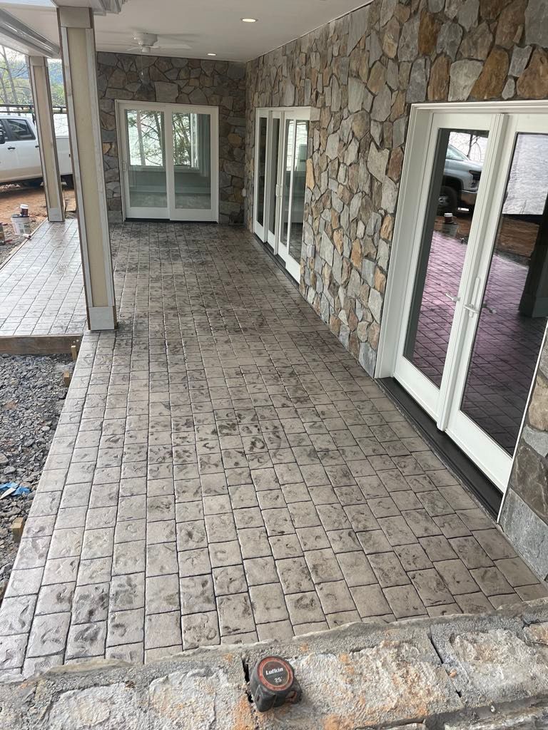 A patio with a stone wall and sliding glass doors.