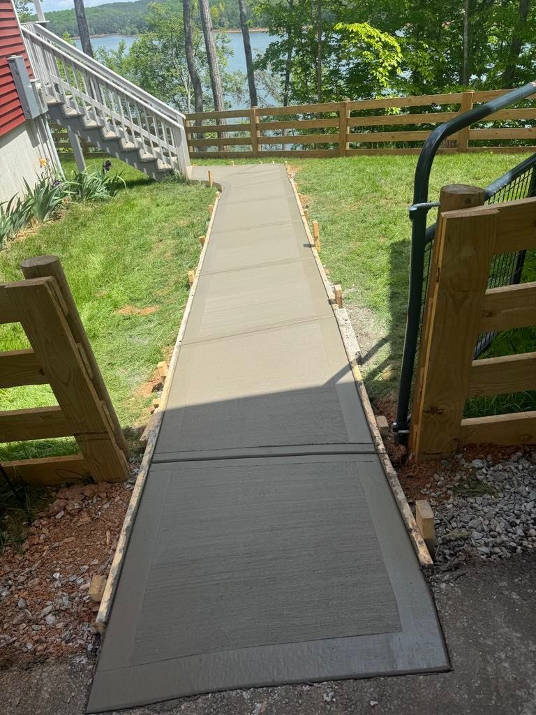 A concrete walkway is being built next to a wooden fence.