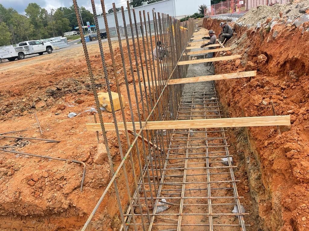 A construction site with a fence being built in the dirt.