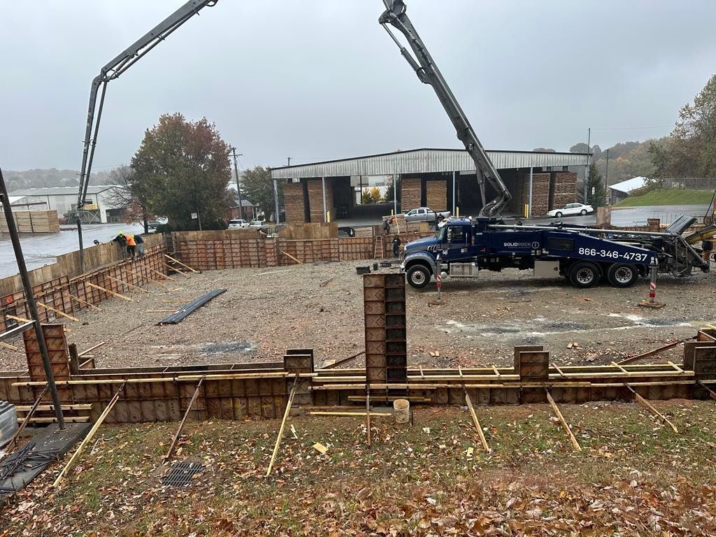 A concrete pump truck is pouring concrete into a building under construction.