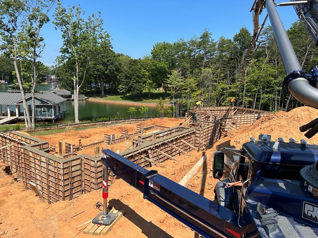 A construction site with a crane in the foreground and a house in the background
