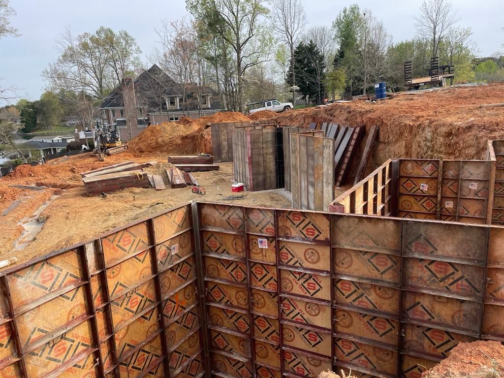 A large concrete wall is being built on top of a dirt hill.
