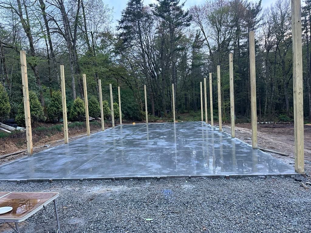 A concrete floor with wooden poles surrounding it is being built.