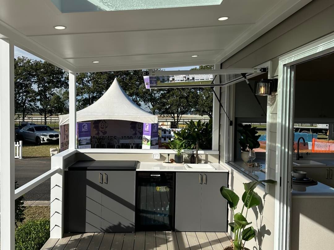 Outdoor Kitchen With Gray Cabinets, Small Fridge, Sink, and White Tent in the Background 