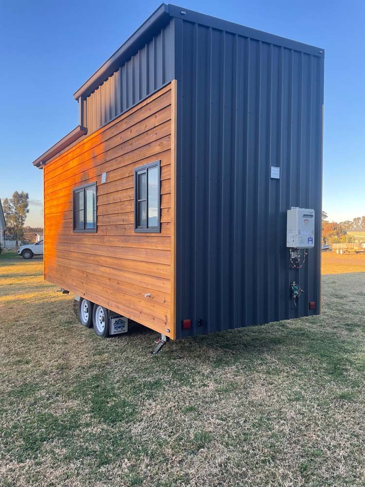 A Tiny House on Wheels is Parked in a Grassy Field — Highlands Tiny Homes In Braemar, NSW