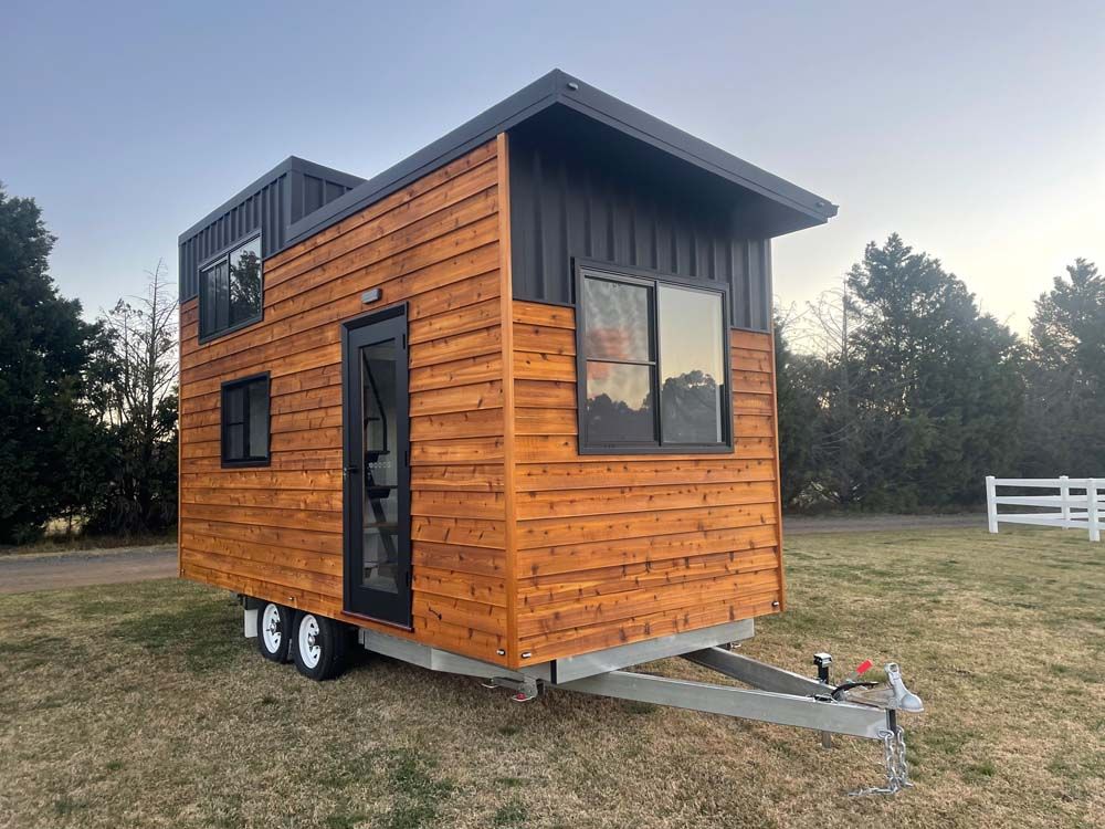 A Small Wooden House on Wheels is Parked in a Field — Highlands Tiny Homes In Braemar, NSW