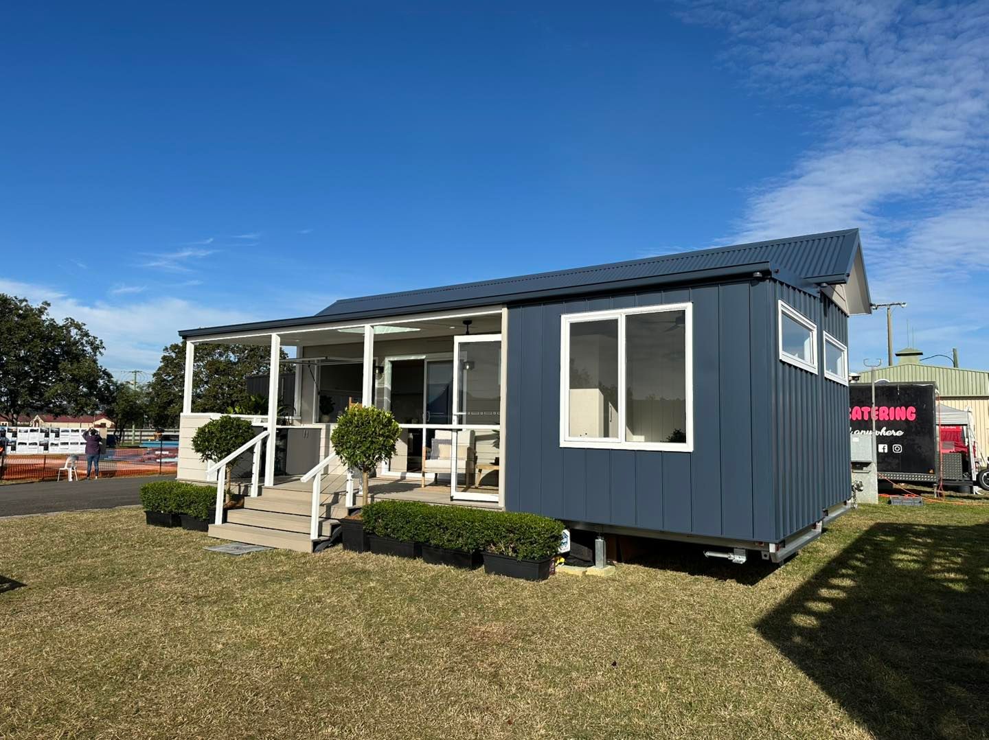 Tiny Blue House With a Porch on Grass Under a Blue Sky — Highlands Tiny Homes In Braemar, NSW