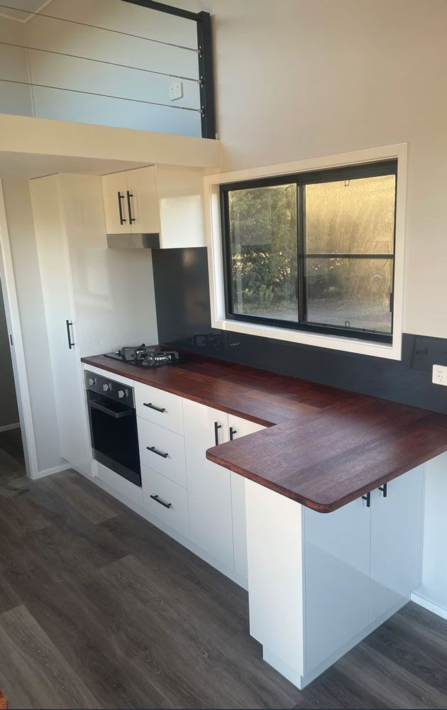 A Kitchen With White Cabinets and a Wooden Counter Top — Highlands Tiny Homes In Braemar, NSW