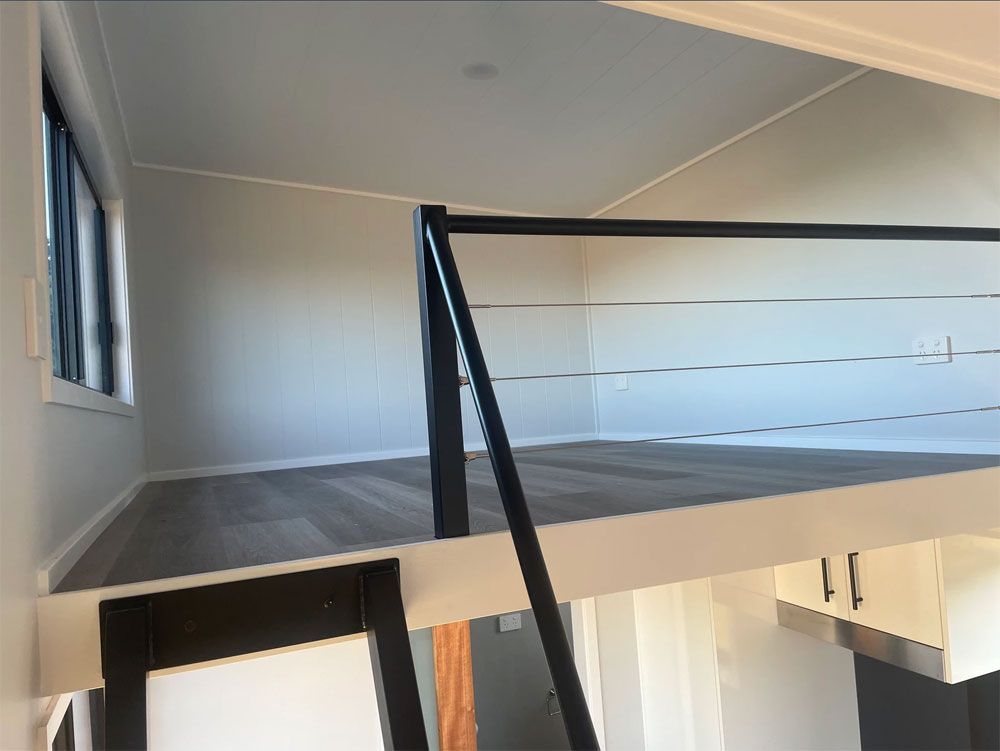 An Empty Room With a Balcony and Stairs Leading to It — Highlands Tiny Homes In Braemar, NSW