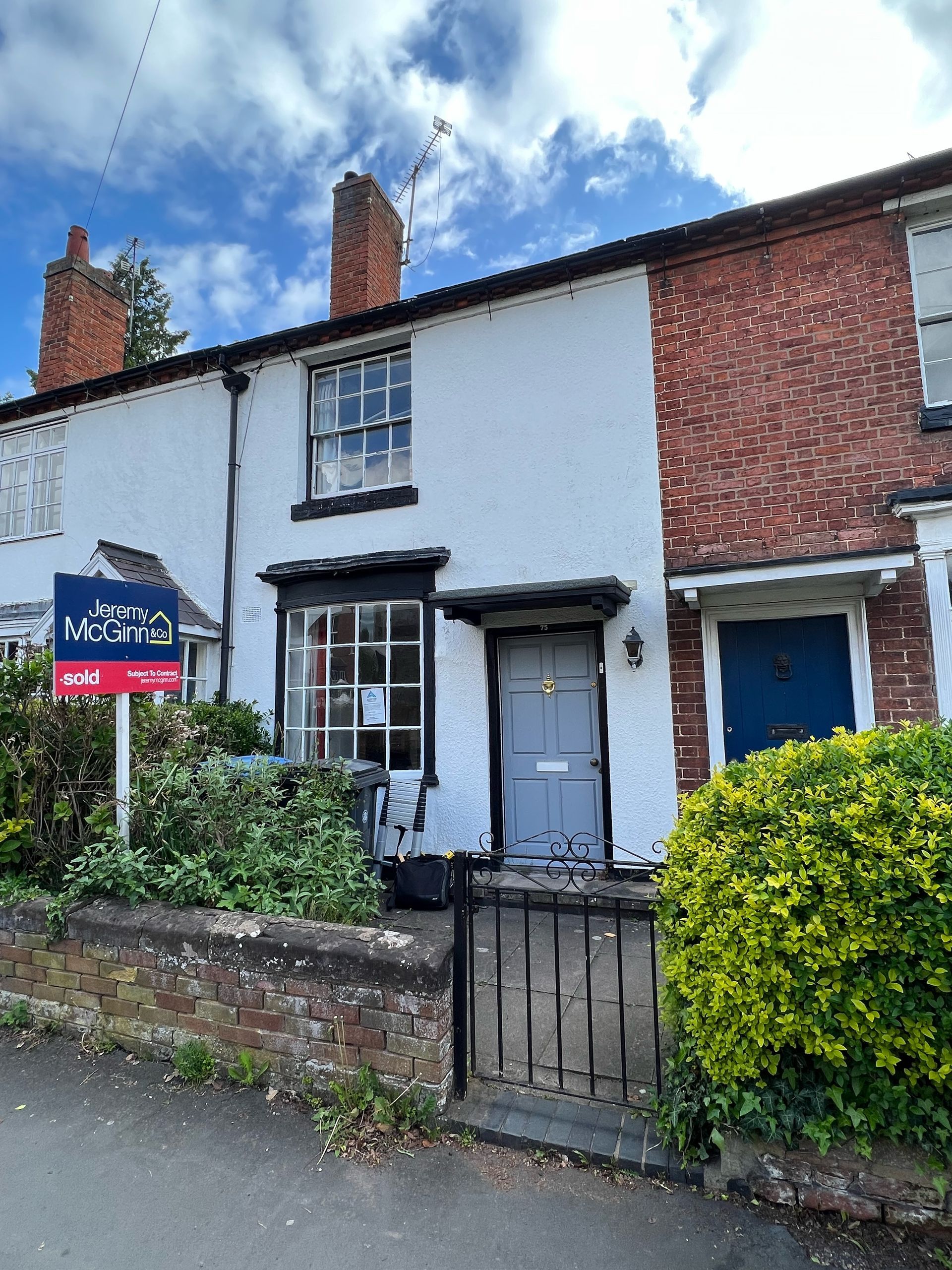 White and brick cottage with dark blue door and window trim; a 