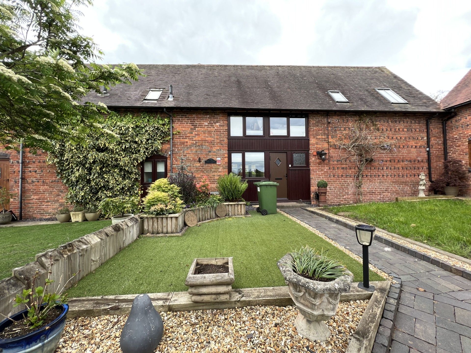 Brick building with lawn and garden in front, cloudy day.