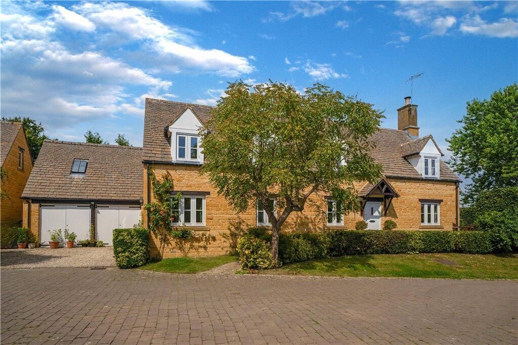 Tan house with garage and thatched roof, tree in front, under blue sky.