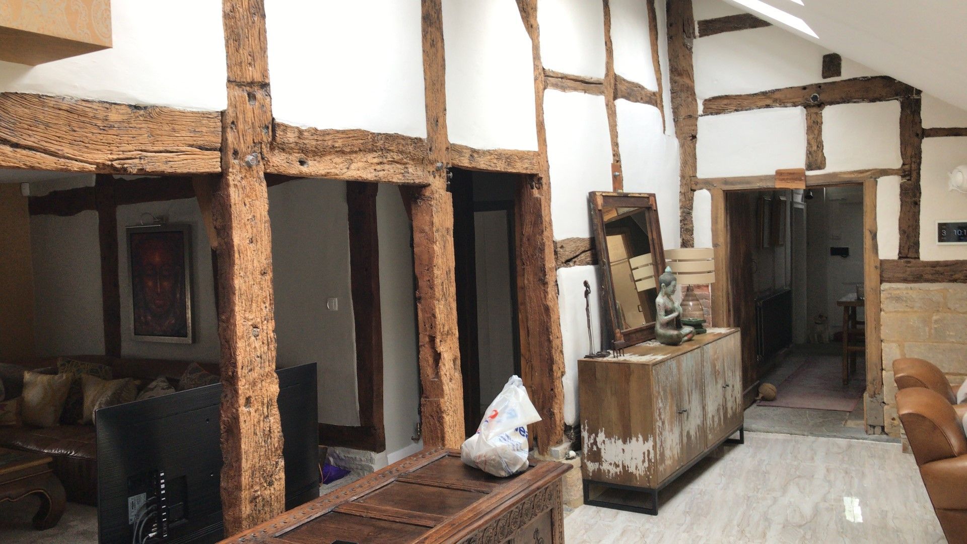 Interior with exposed wooden beams, white walls, and a living area with furniture.