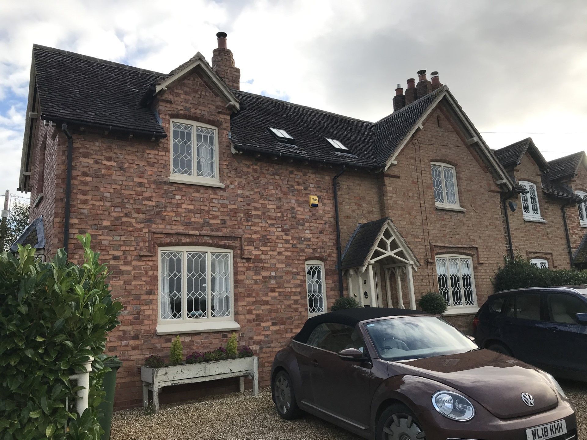 Brick house with a maroon car parked in front. White-framed windows and a small front porch.