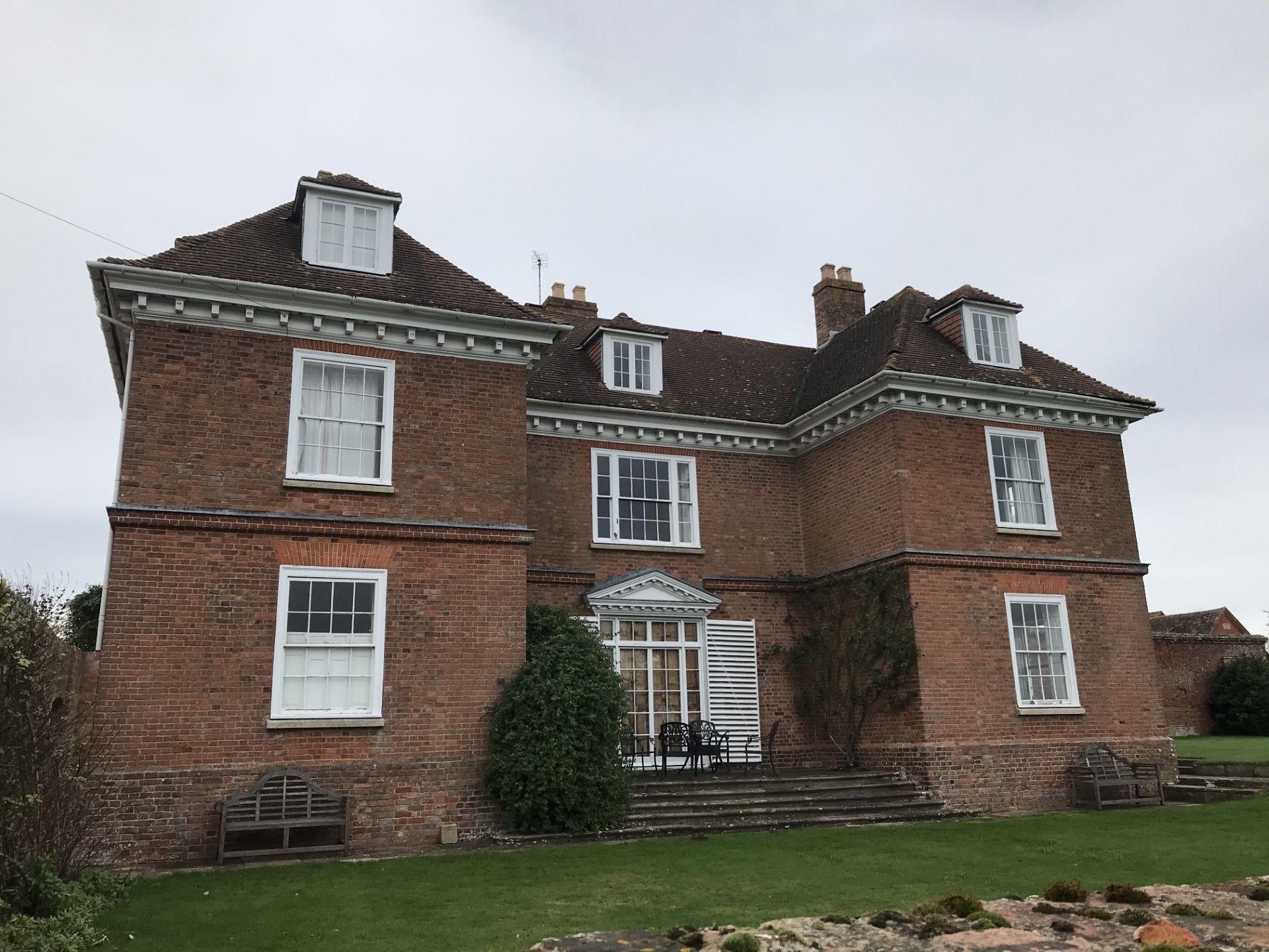 Red brick mansion with white window frames and a glass entrance.