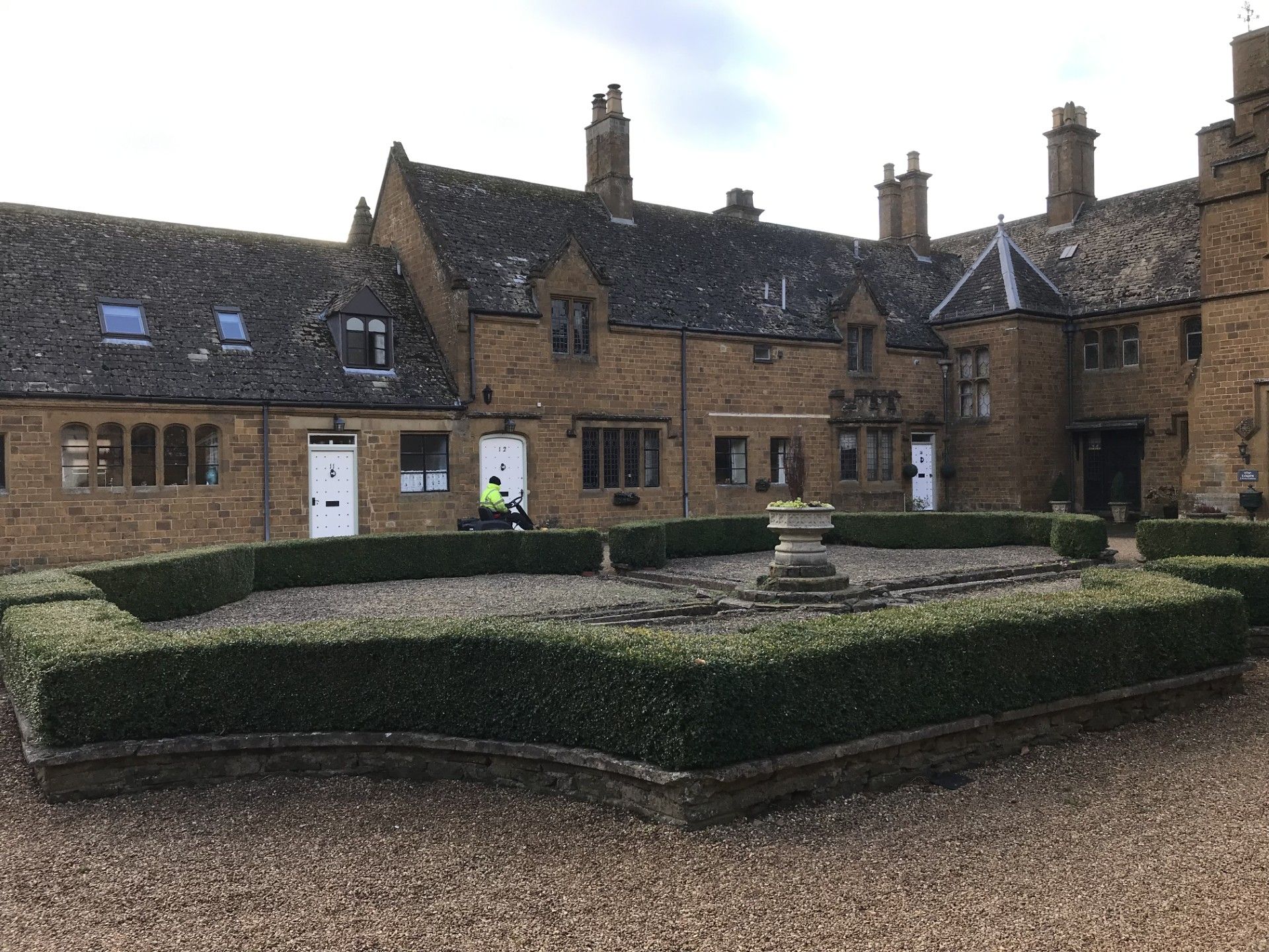 Stone building with hedge garden and gravel path.