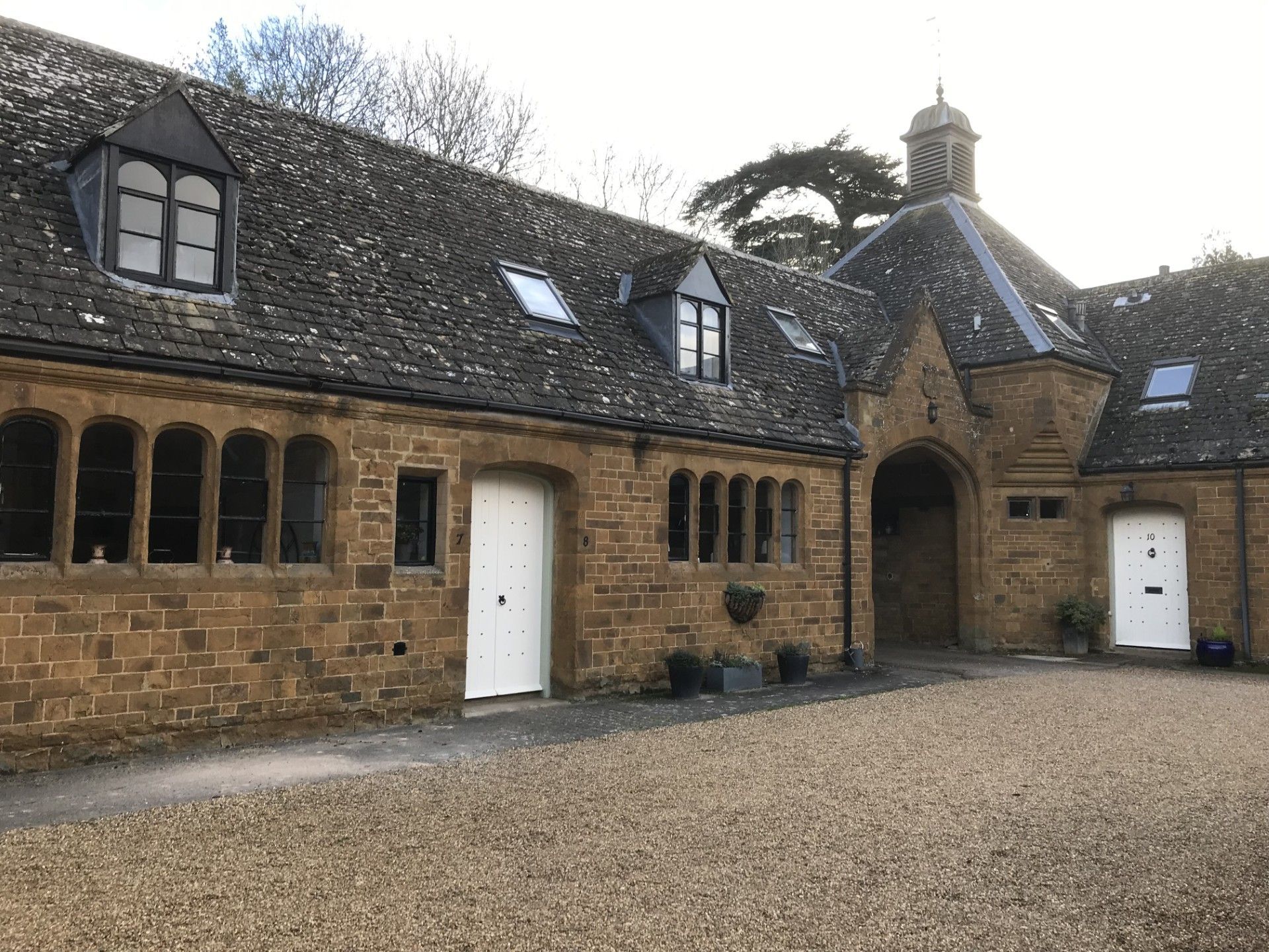 Stone building with arched windows and a gravel driveway.