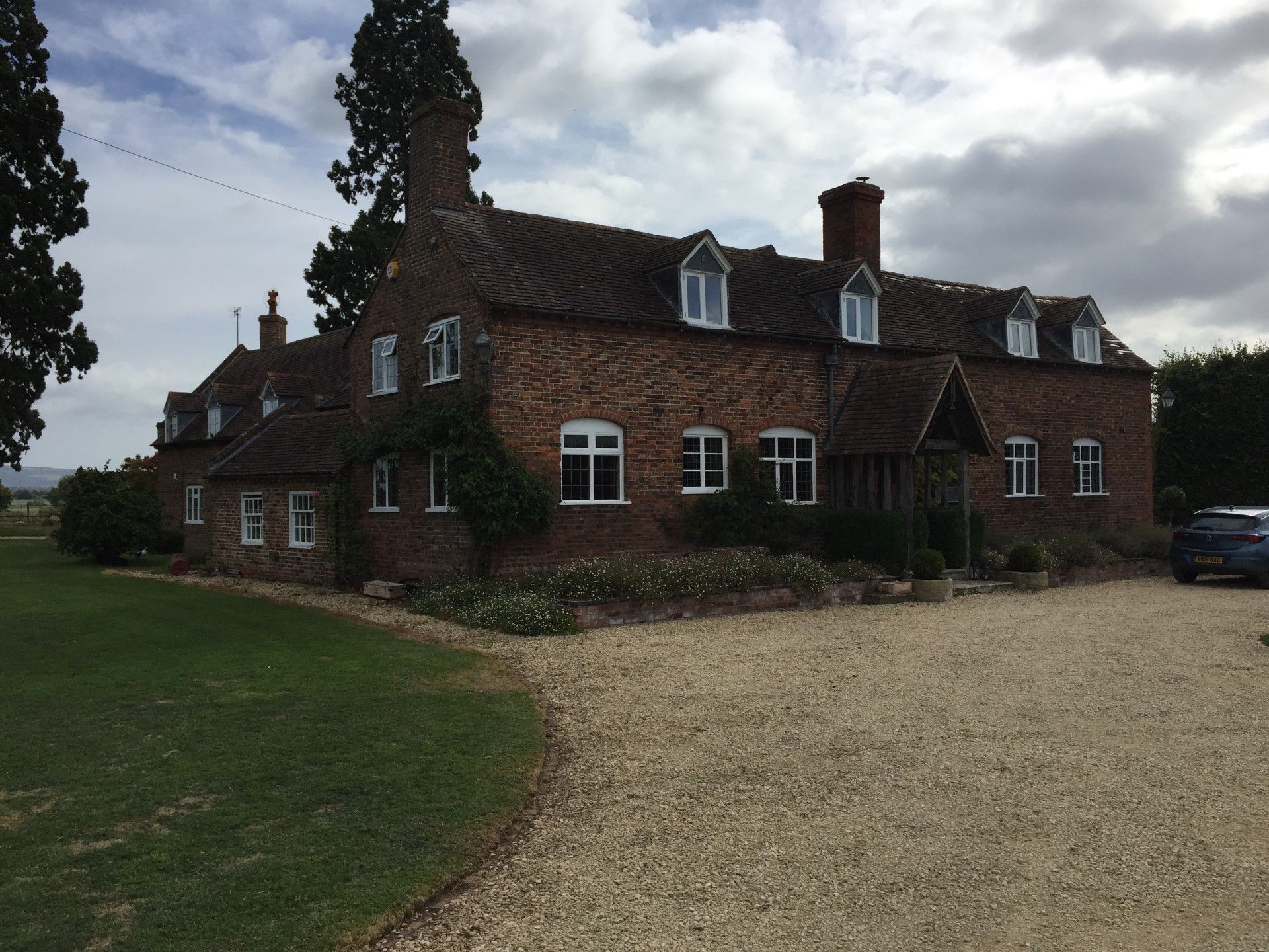 Brick house with multiple dormers and a gravel driveway.