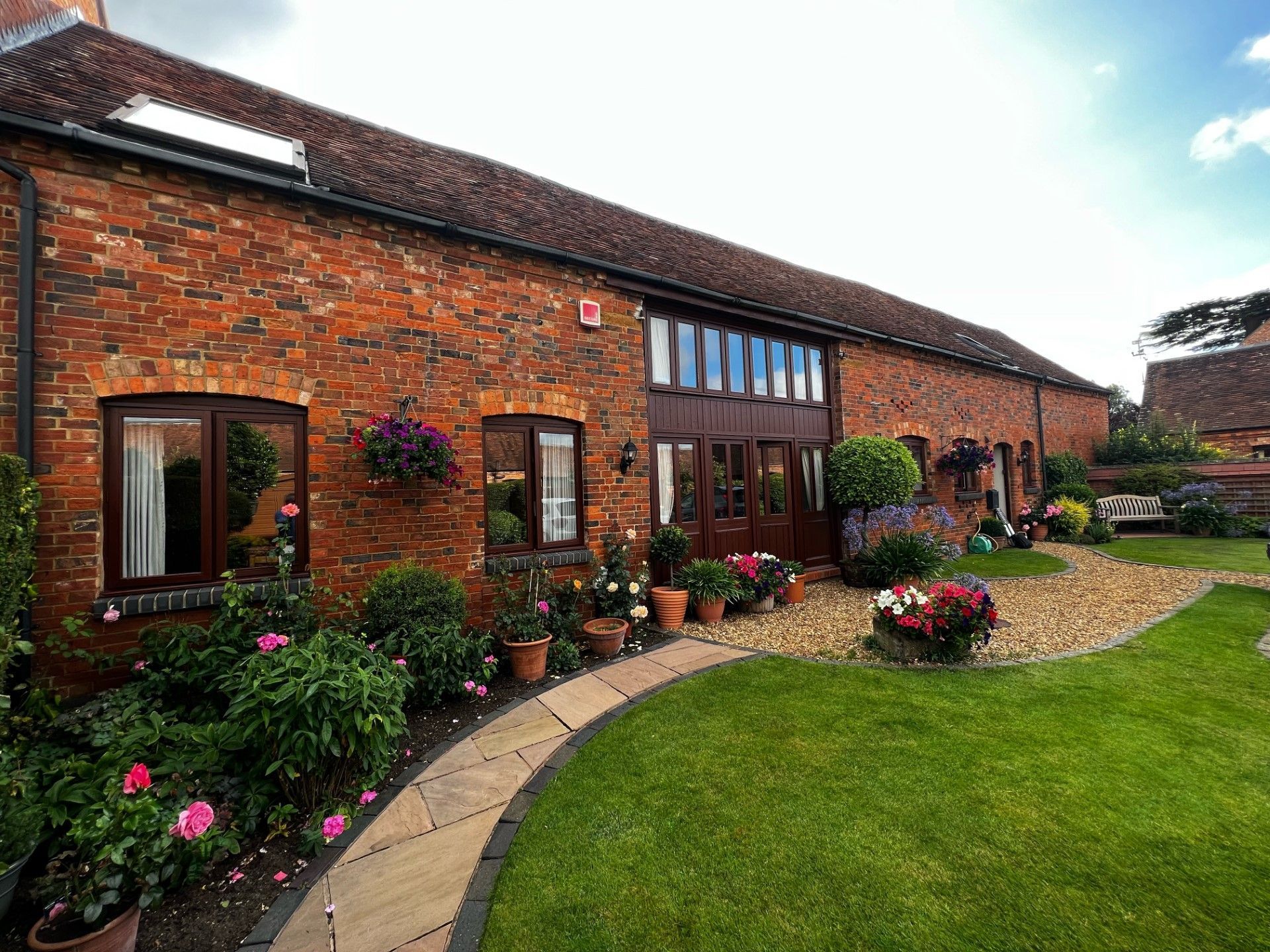 Brick building with brown doors, windows, and flower pots in a green garden.