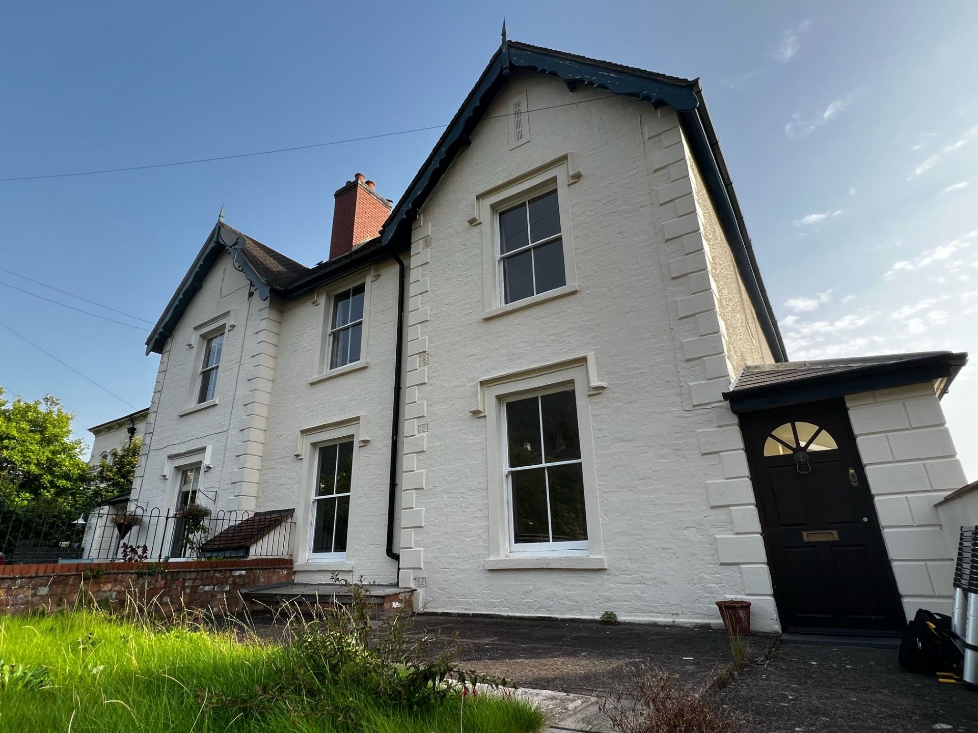 White house with black trim and door; green lawn in foreground.
